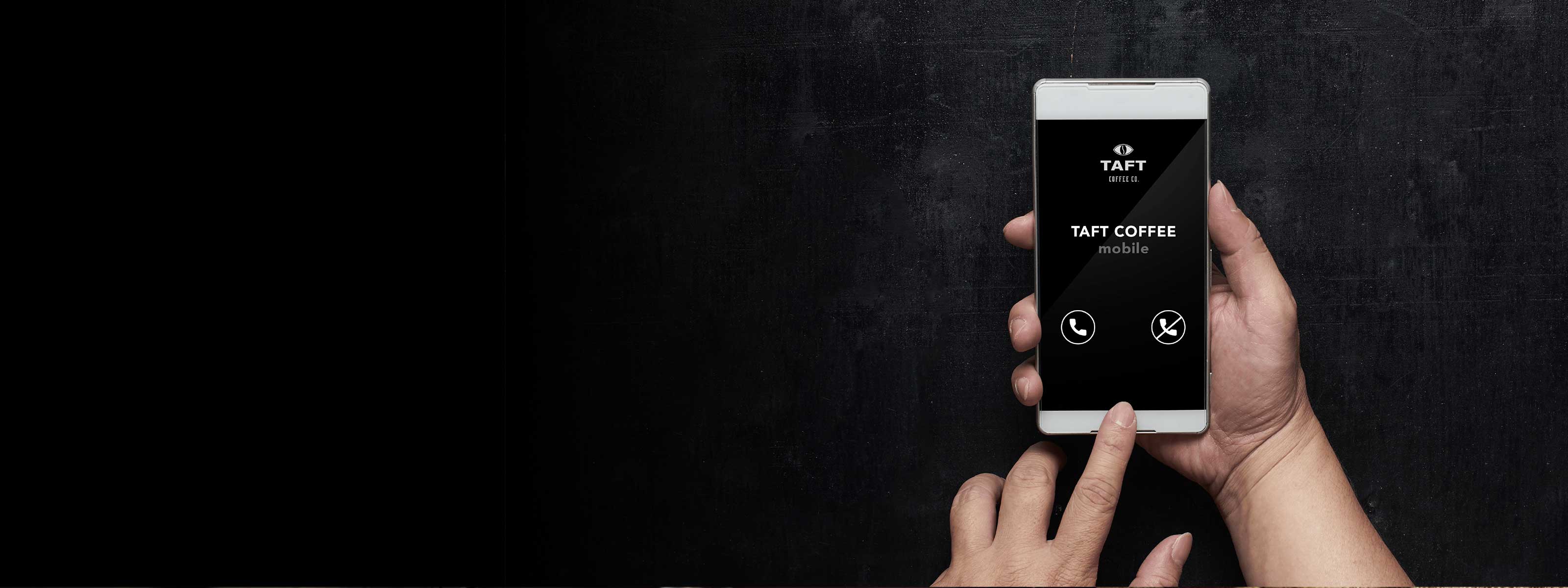 Siyah arka planın yer aldığı görselin sağ tarafında sağ eliyle telefon üzerinden TAFT Coffee'ye giriş yapan kişinin, sol işaret parmağıyla ekrana dokunma anı yer alıyor.