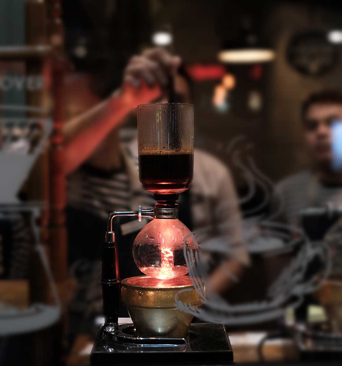 Kalabalık bir insan grubunun önünde filtre kahve demlenen Syphon kahve demleme ekipmanı.