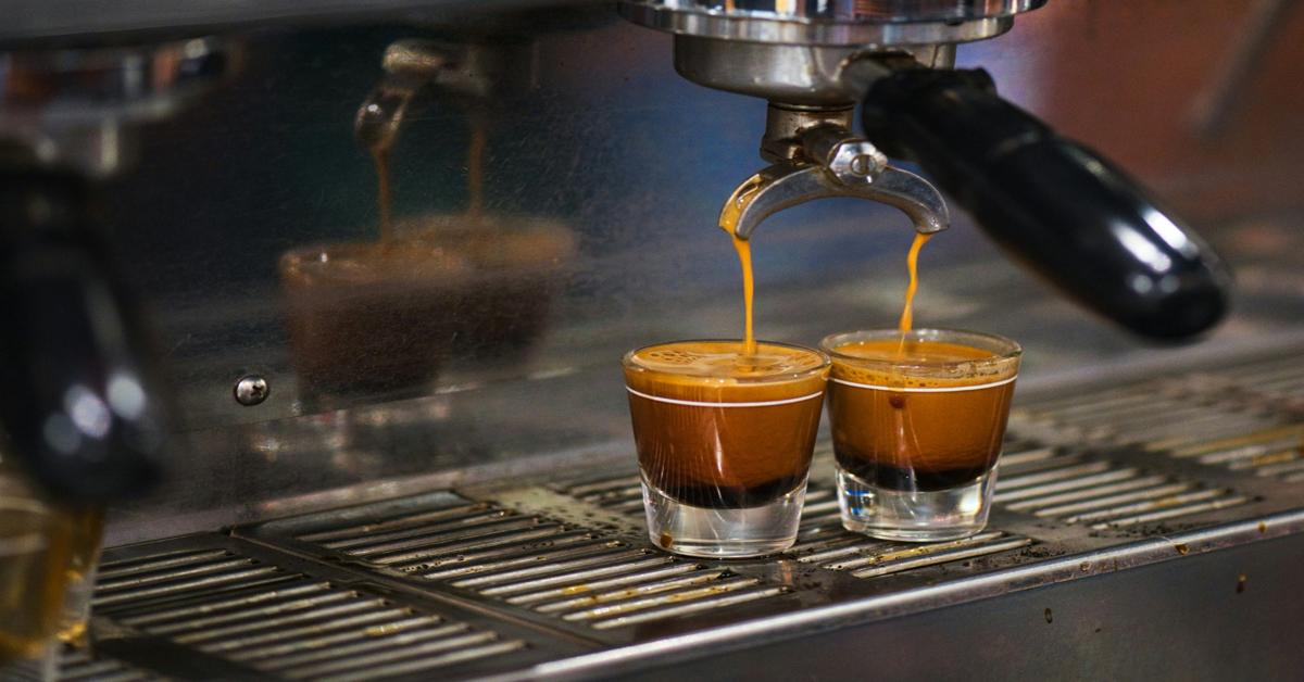 Taze demlenmiş iki espresso shot'ı, altın krema ve zengin dokuyu yakalayarak bardaklara akarken.