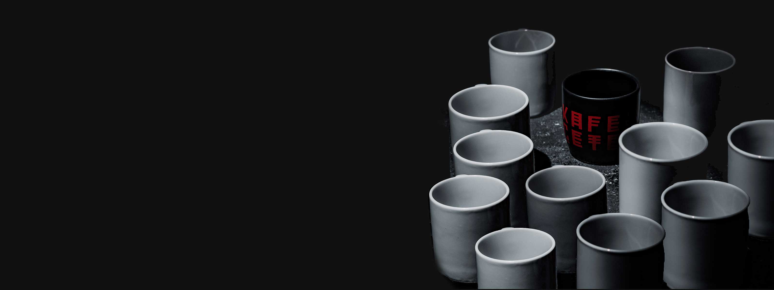 Beyaz renkli kupaların yanında yer alan siyah renkli "Kafein Çetesi" yazılı TAFT kupası.