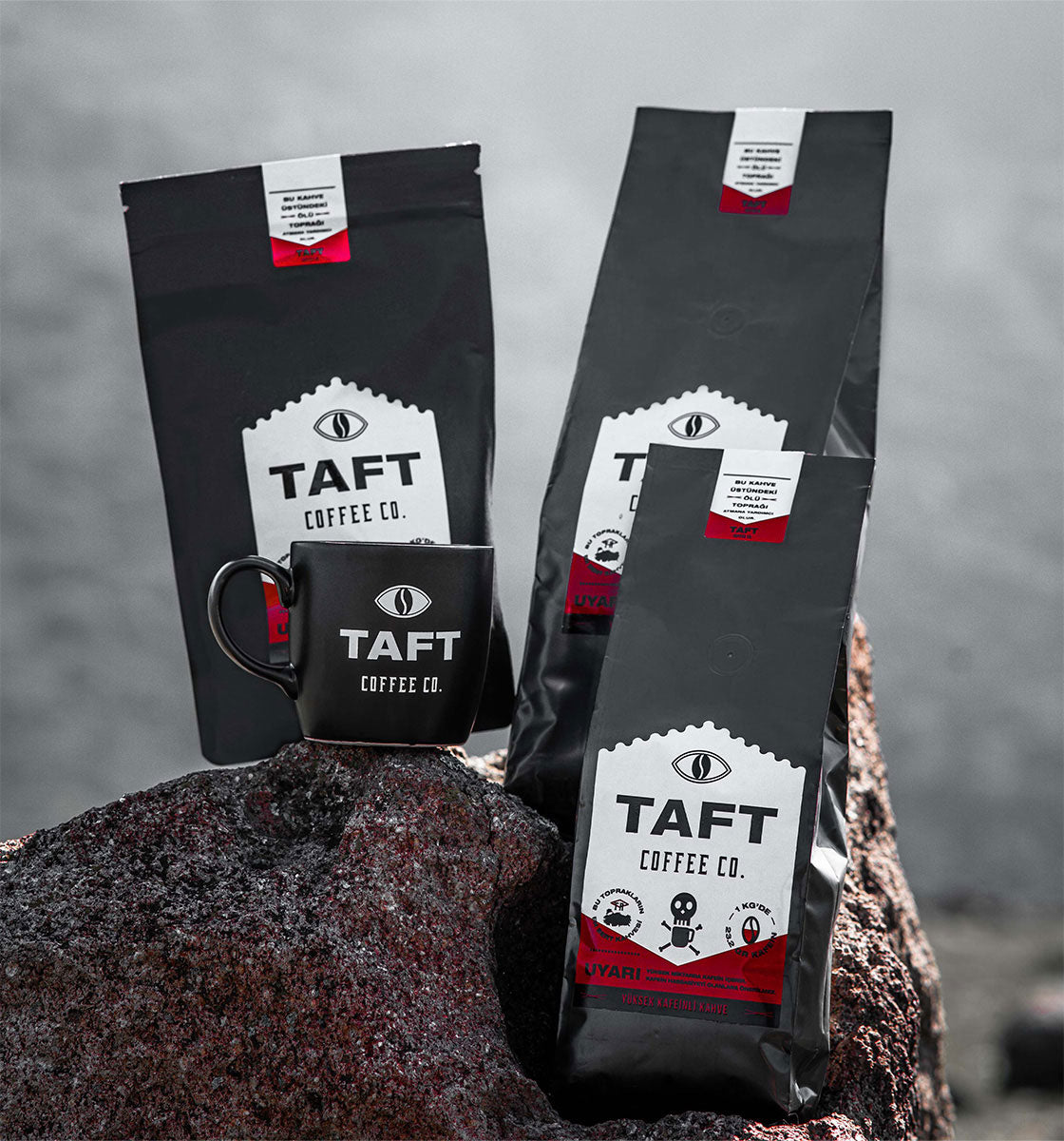 Açık havadaki kaya üzerinde yer alan TAFT Kahve paketleri ve TAFT Kupa.