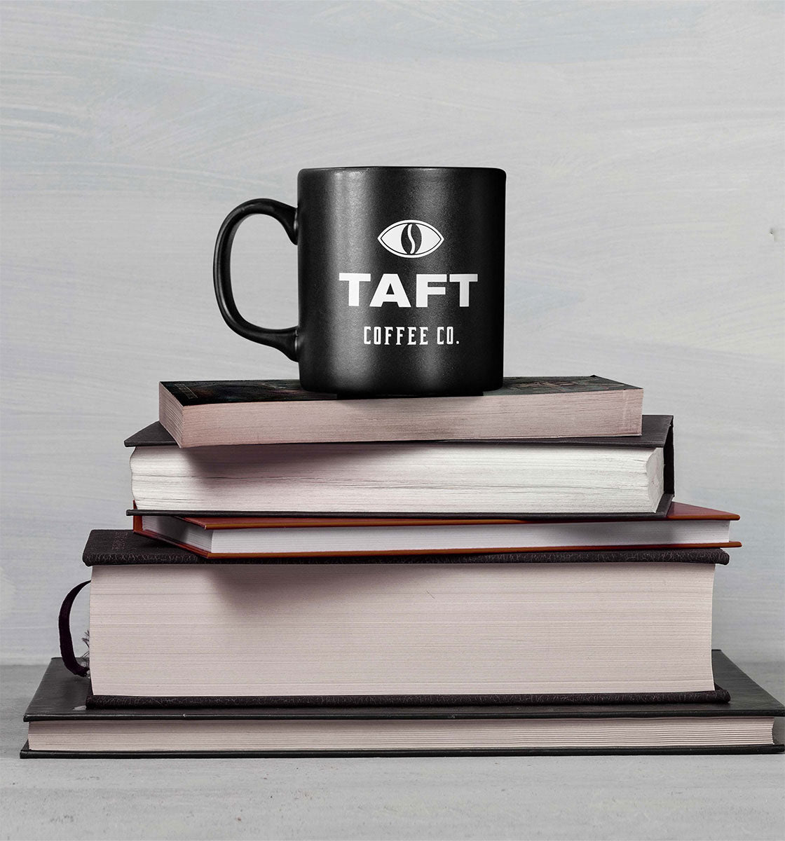 Açık renkli bir arka planda üst üste dizilmiş beş kitabın üzerine yerleştirilmiş TAFT Kupa.